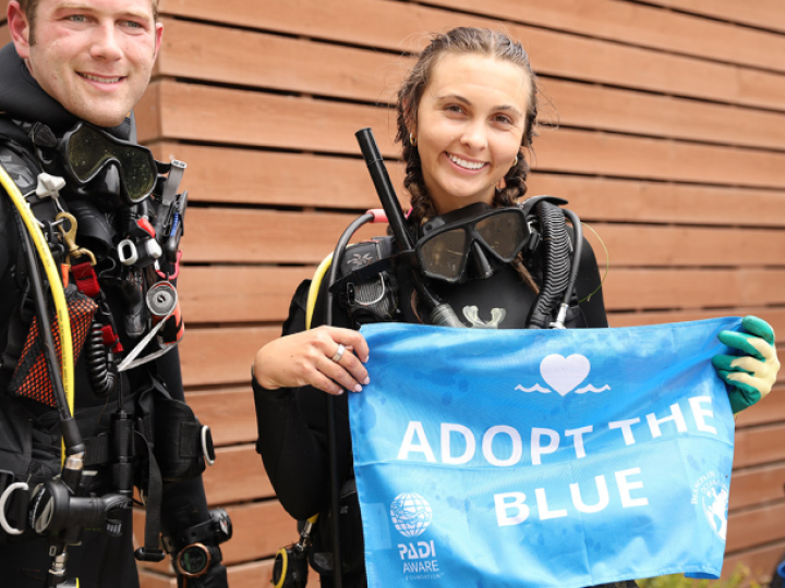Diver holding a blue Adopt the Blue flag.